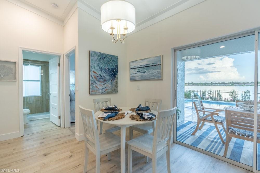 6831 Mill Pond Circle Naples, FL 34109 - Photo 9 of 45 a view of a dining room with furniture wooden floor and a chandelier