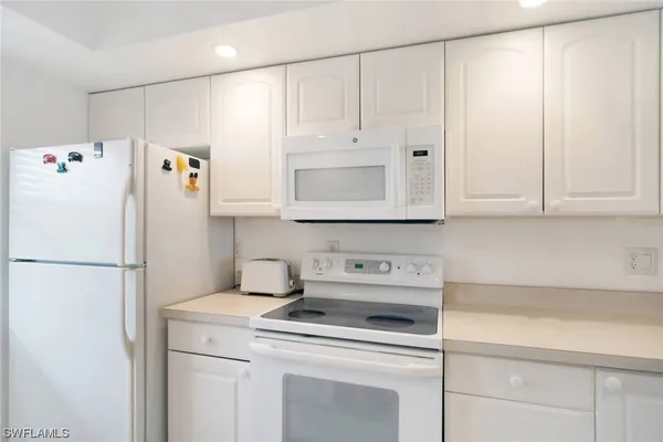a kitchen with kitchen island white cabinets appliances and a sink