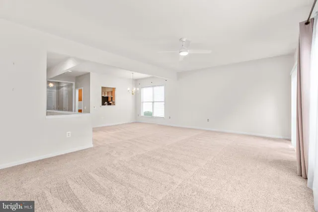 a view of a big room with a chandelier fan and front door