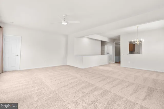 an empty room with windows and chandelier fan