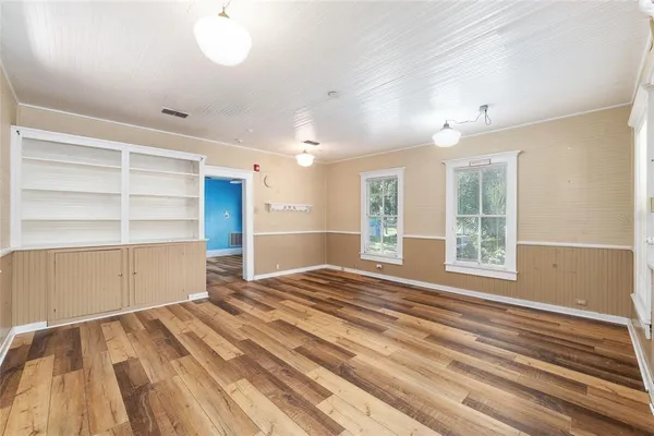 a view of an empty room with wooden floor and a window