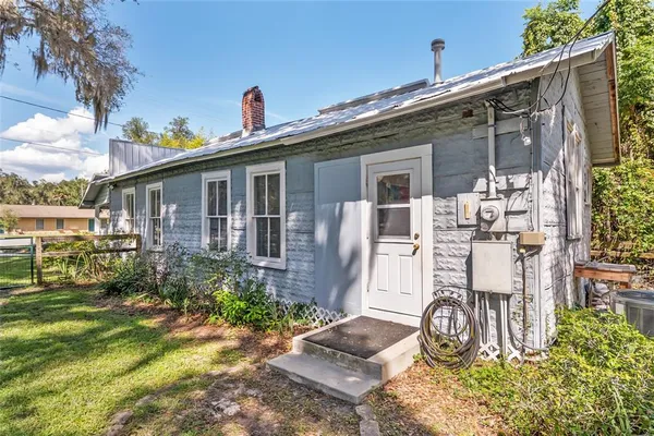 a view of backyard of house with outdoor seating and trees