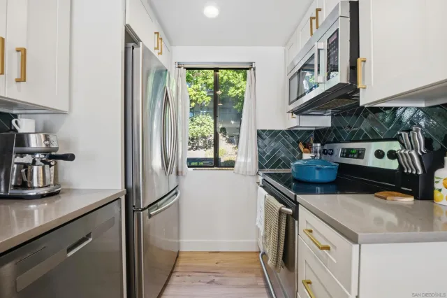 a kitchen with stainless steel appliances granite countertop a refrigerator a stove and a sink with wooden floor