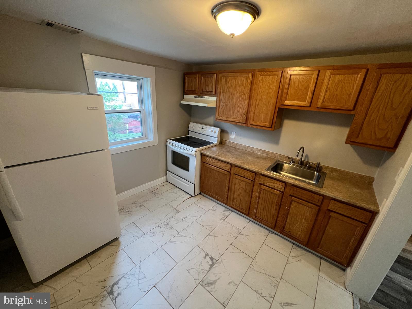 1025 Elton Avenue Baltimore, MD 21224 - Photo 11 of 11 a kitchen with stainless steel appliances granite countertop a refrigerator sink and cabinets