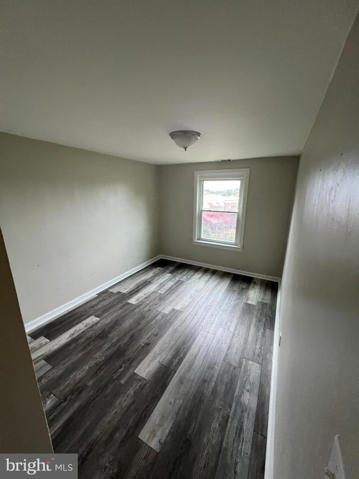 1025 Elton Avenue Baltimore, MD 21224 - Photo 6 of 11 an empty room with wooden floor and windows