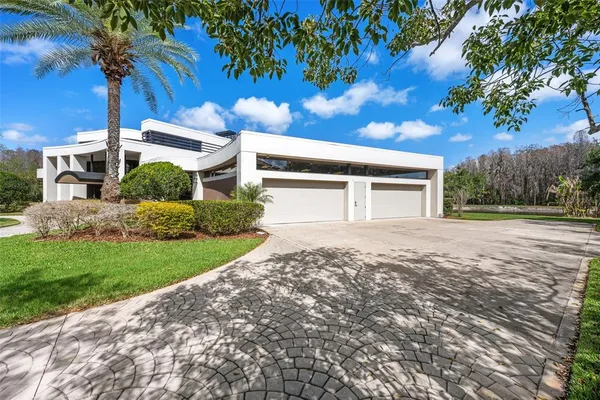 a view of a white house with a big yard and potted plants