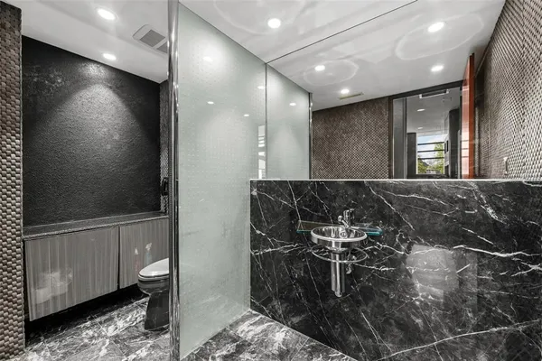a bathroom with a granite countertop toilet sink and mirror