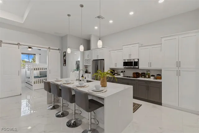 a kitchen with stainless steel appliances kitchen island granite countertop a table chairs stove and white cabinets