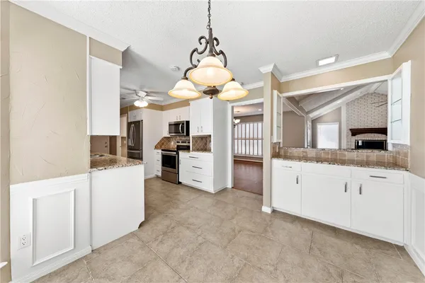 a large white kitchen with granite countertop a sink and dishwasher a stove top oven with white cabinets