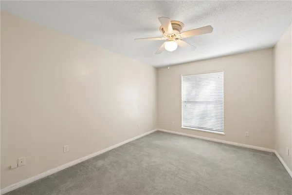 an empty room with a window and a fan