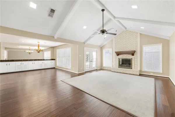 an empty room with wooden floor fireplace and windows