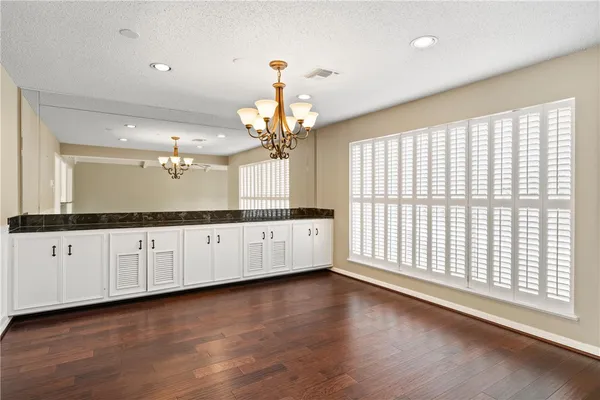 a large white kitchen with granite countertop a large window and white cabinets