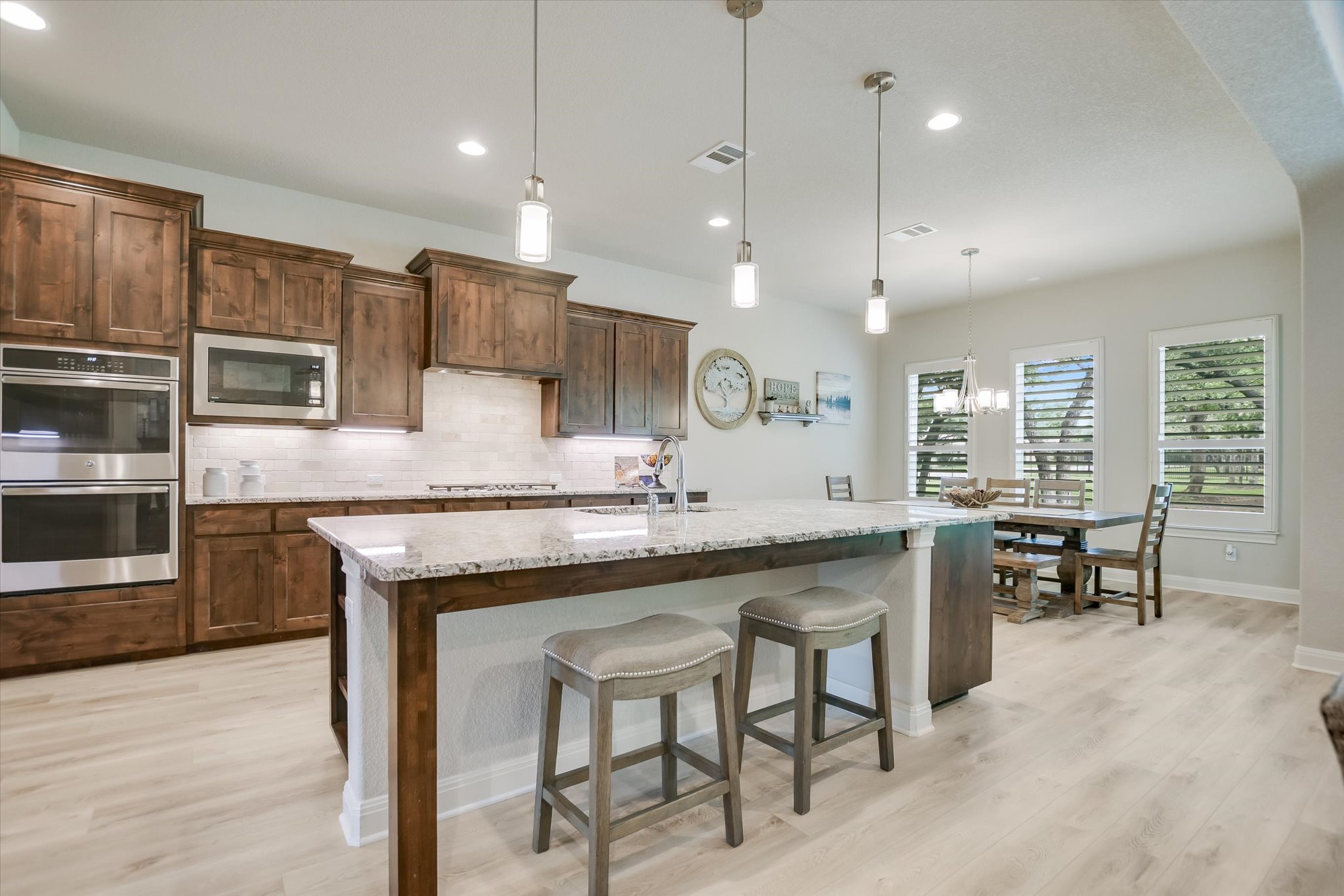 2561 Ridley House Cove Leander, TX 78641 - Photo 4 of 36 Kitchen featuring dark wood cabinetry, stainless steel double ovens, a built-in microwave, and a tile backsplash
