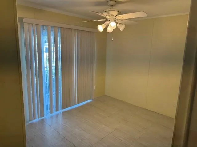an empty room with wooden floor and fan view