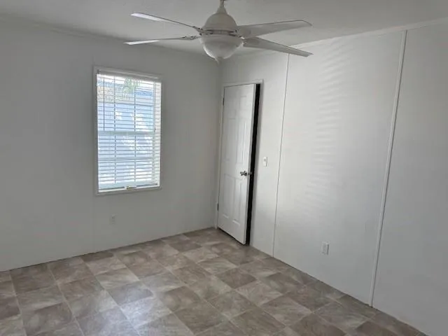 an empty room with windows and fan