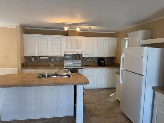 a kitchen with a refrigerator a sink and white cabinets