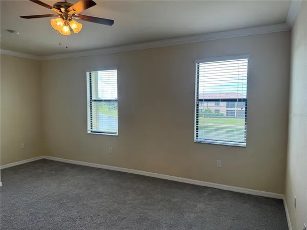 an empty room with ceiling fan and windows