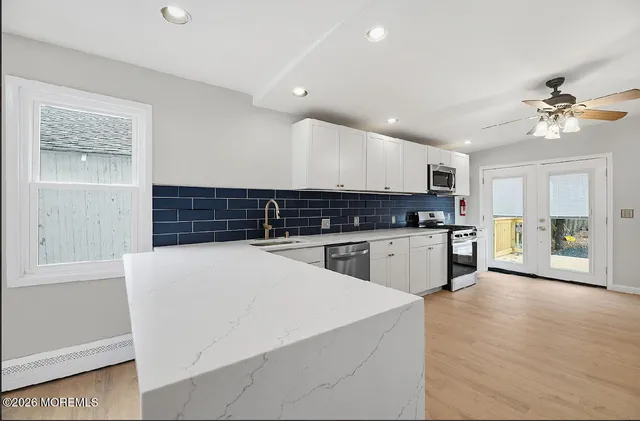 a large white kitchen with kitchen island a sink stainless steel appliances and cabinets