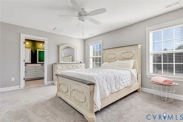 a spacious bedroom with a bed a dresser and potted plant on the dresser