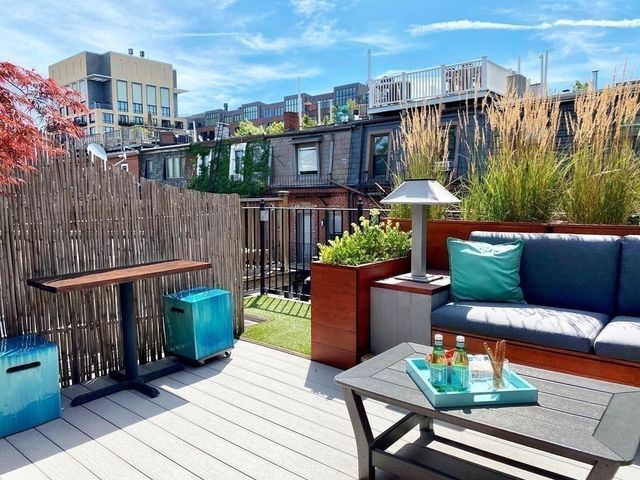 a balcony with couple of flower plants and wooden fence