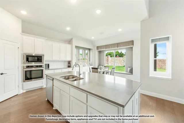 a kitchen with stainless steel appliances granite countertop a stove a sink a refrigerator and white cabinets