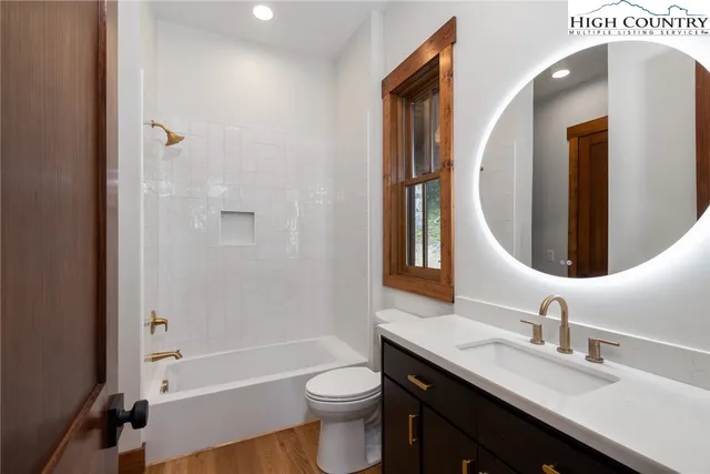 a bathroom with a double vanity sink toilet mirror and bathtub