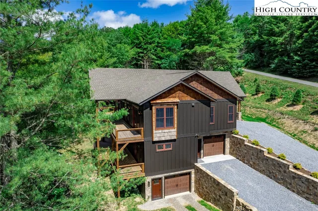 an aerial view of a house with yard and trees in the background