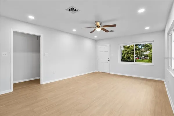 an empty room with windows and ceiling fan