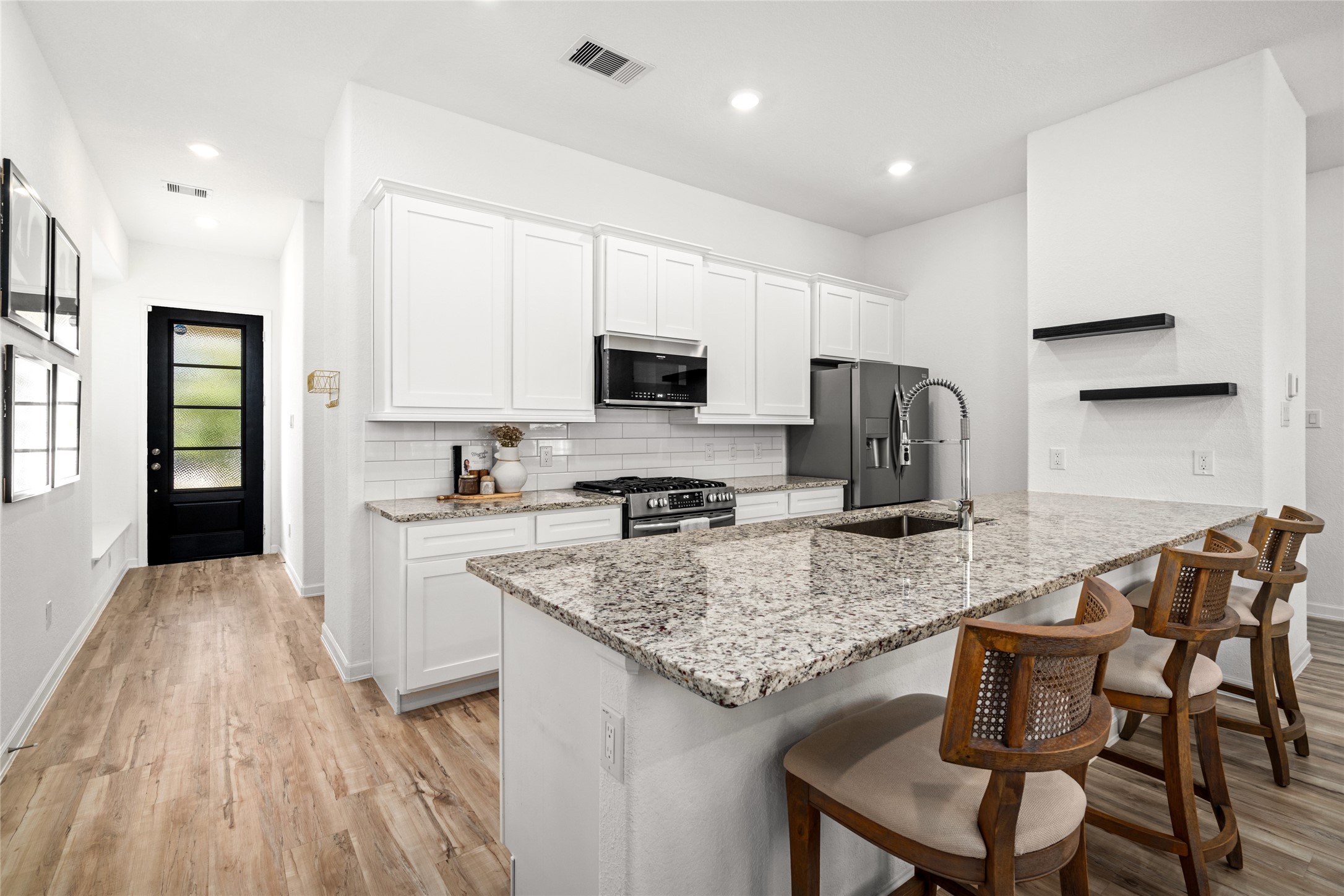 575 Dry Fork Lane Conroe, TX 77304 - Photo 5 of 34 a kitchen with stainless steel appliances granite countertop a stove top oven a sink dishwasher and a refrigerator with wooden floor