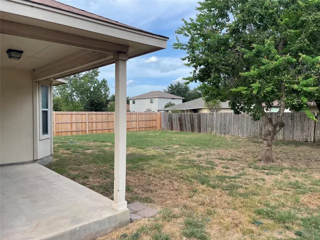 a view of a backyard with large trees and wooden fence