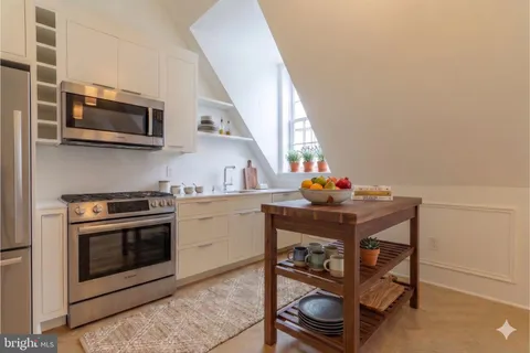 a kitchen with stainless steel appliances a stove a microwave and white cabinets