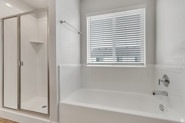 4572 Flower Point Eagle Mountain, UT 84005 - Photo 40 of 62 Full bathroom featuring a shower with a clear glass enclosure, a built-in shower shelf, a white bathtub, and chrome fixtures