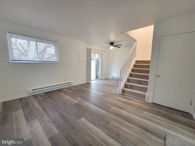 a view of an empty room with wooden floor and stairs