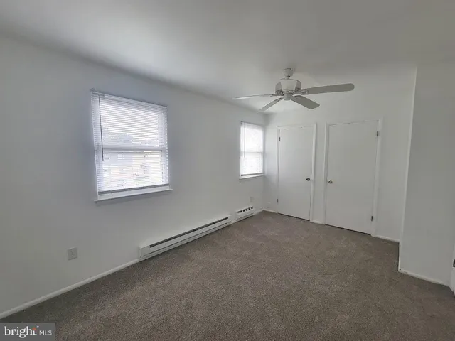 an empty room with windows and fan