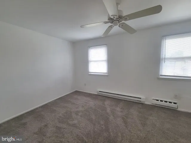 an empty room with windows and fan