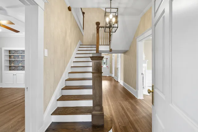 an empty room with windows a fireplace a ceiling fan and wooden floor