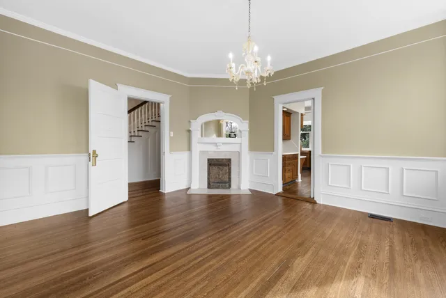 an empty room with wooden floor fireplace and windows