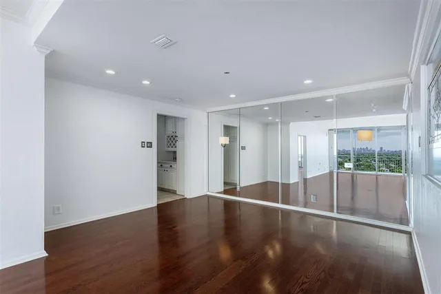 an empty room with wooden floor and natural light