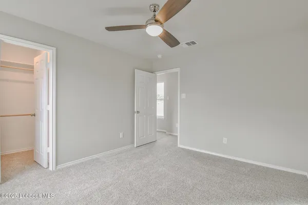 an empty room with a fan & a window