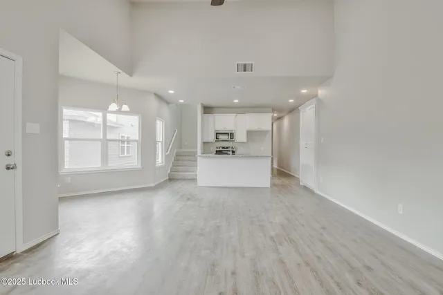 a view of a electric appliances in kitchen and empty room with wooden floor