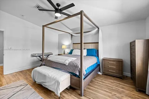 a bedroom with a bed a dresser and wooden floor