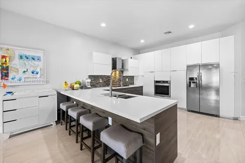a kitchen with a refrigerator a sink cabinets and wooden floor