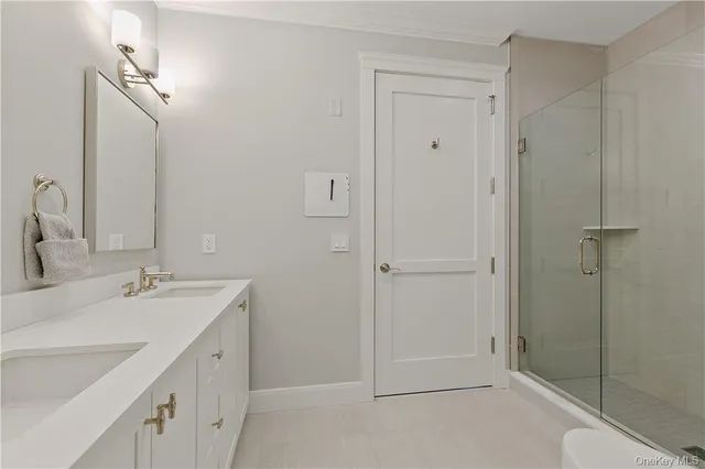 a bathroom with a double vanity sink mirror and shower