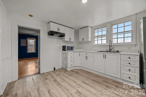a kitchen with granite countertop a sink cabinets and a wooden floor