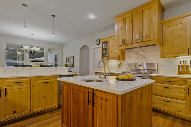 a kitchen with stainless steel appliances granite countertop a sink a stove and cabinets