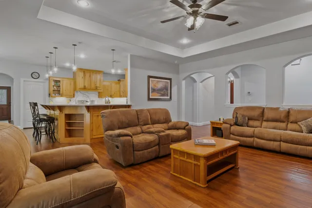 a living room with furniture kitchen view and a chandelier