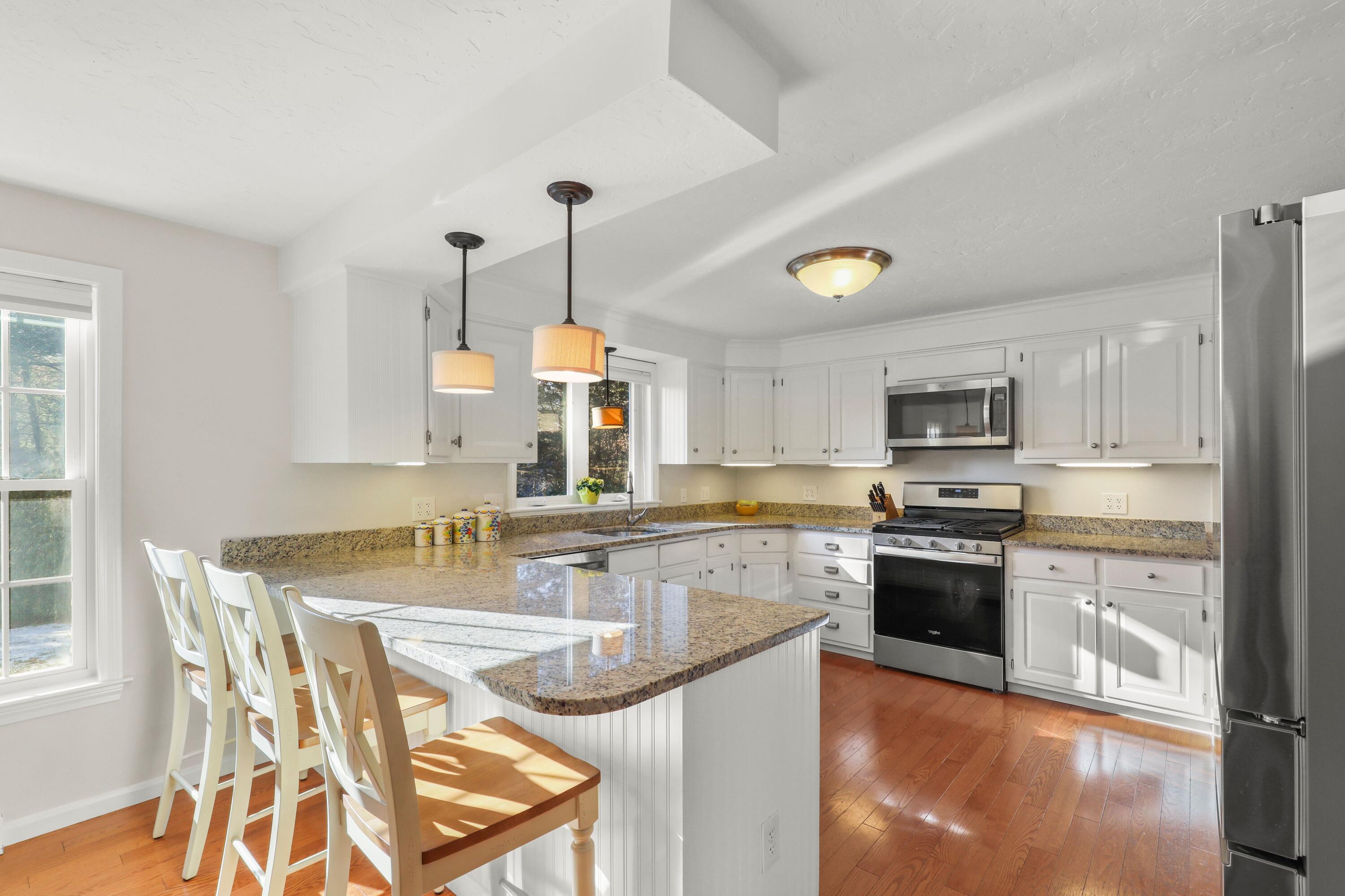 5 Vesper Drive Pocasset, MA 02559 - Photo 7 of 20 a kitchen with stainless steel appliances granite countertop a stove top oven a sink a dining table and chairs with wooden floor
