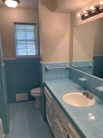 a bathroom with a granite countertop sink a toilet and a mirror