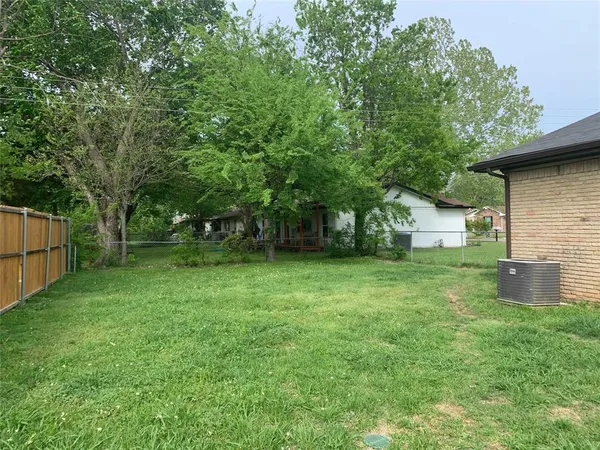 a backyard of a house with plants and large tree