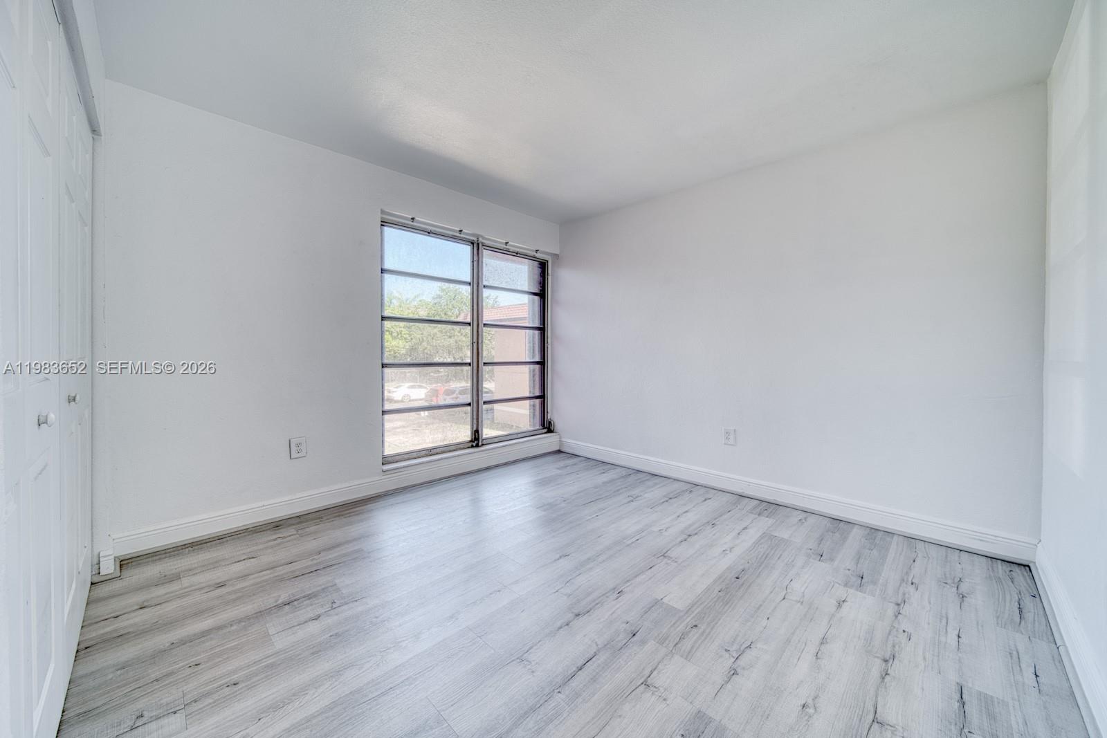 9459 Southwest 76th Street, Unit R5 Miami, FL 33173 - Photo 14 of 33 an empty room with wooden floor and windows